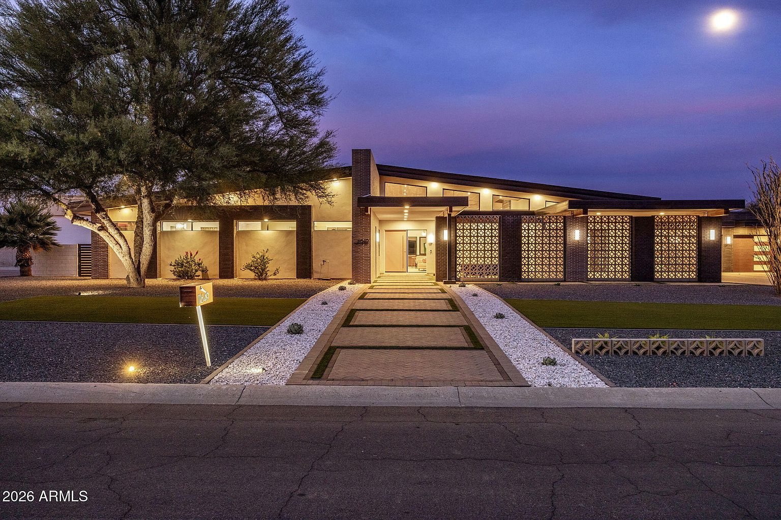Twilight front elevation at 11649 N Miller Road: breeze-block screen walls, low mid-century rooflines, and the moon rising over Scottsdale.